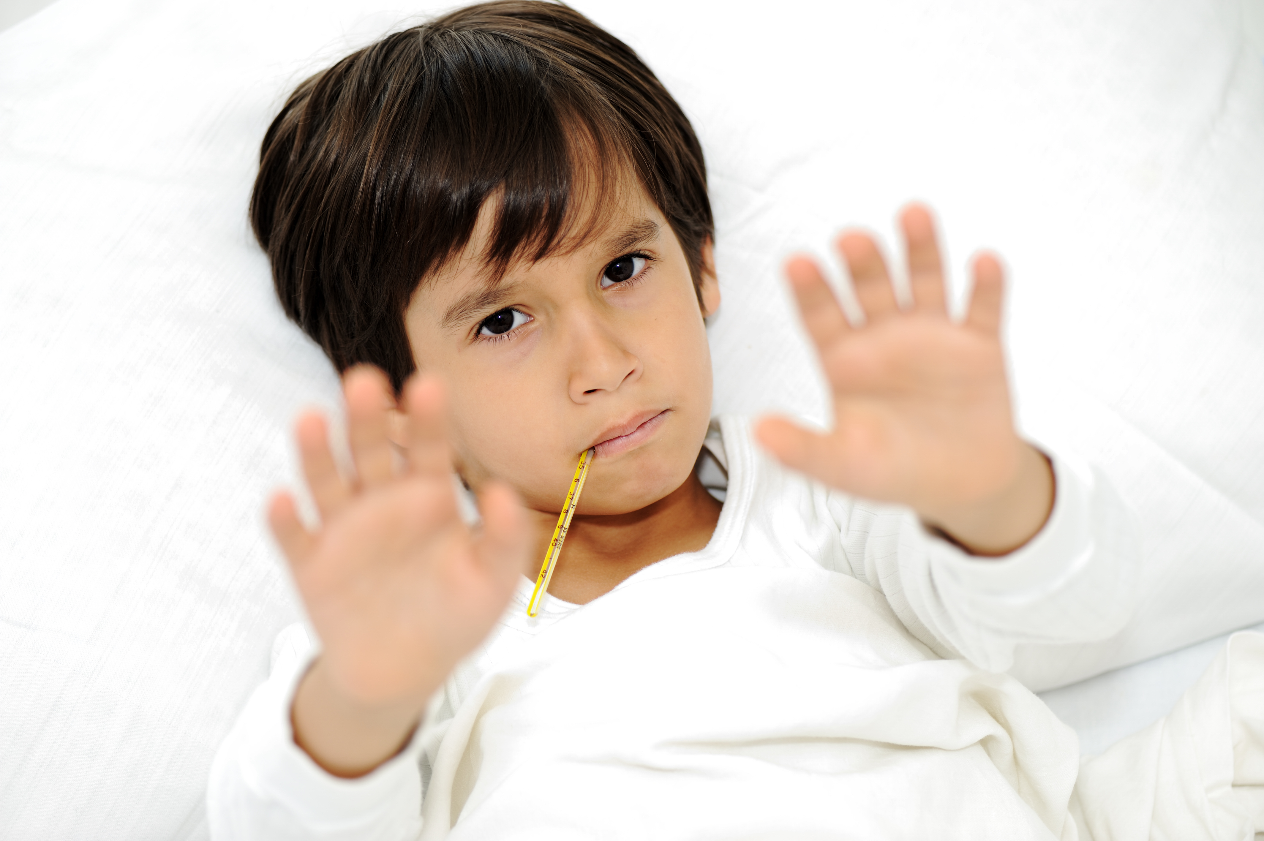 Sick little boy with thermometer, laying on bed